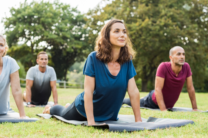 Middle aged woman doing yoga in a park to support her physical wellness and mental health. 